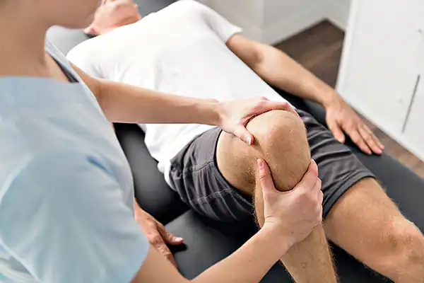 Physical therapist examining patient's knee pain.